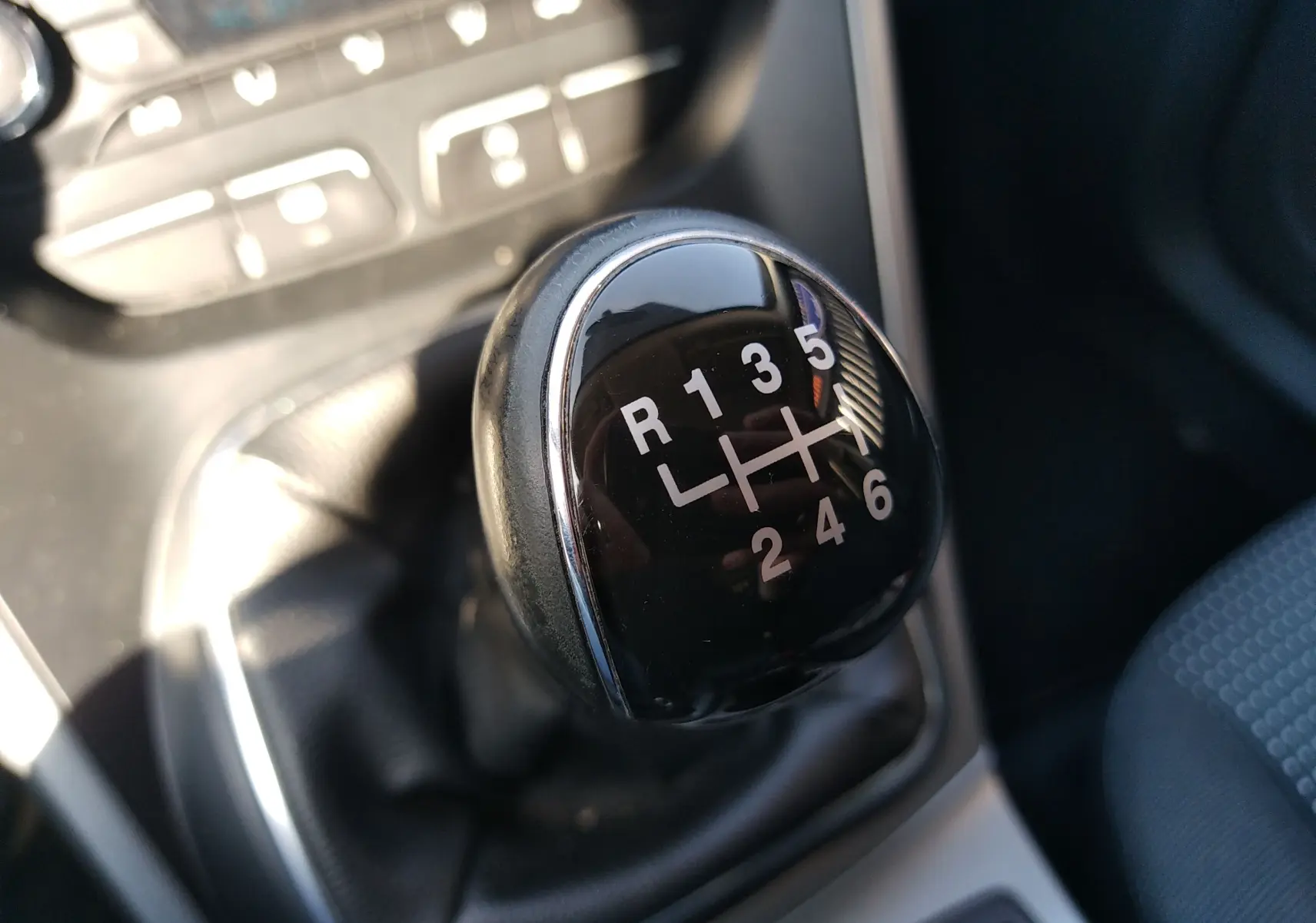 Gros plan sur le levier de vitesses manuel noir de la Ford C-MAX blanc, montrant les six rapports et la marche arrière.