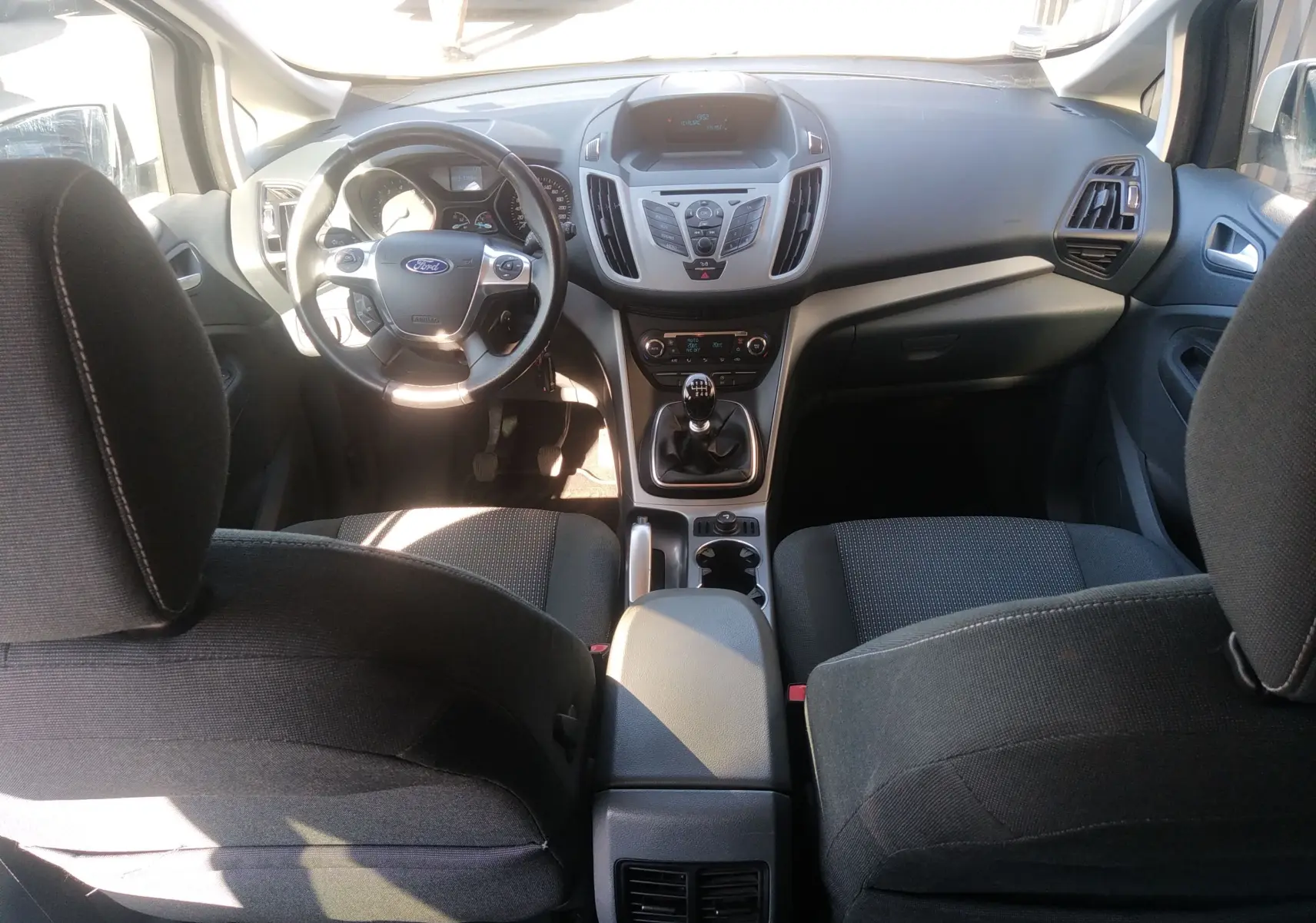 Vue intérieure avant du Ford C-MAX blanc 2013, montrant le tableau de bord, volant multifonction et levier de vitesse manuel.