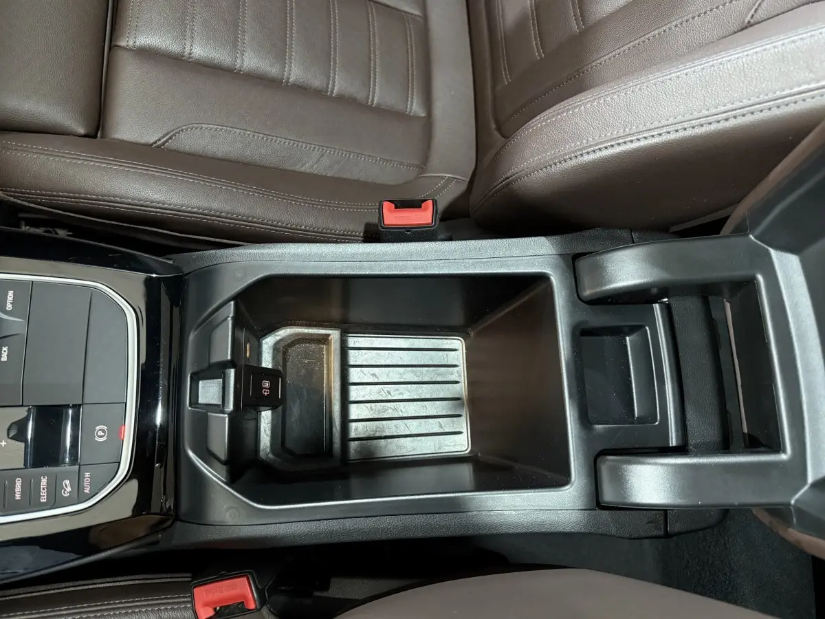 Vue plongeante sur la console centrale noire et les sièges en cuir marron du BMW X3 xDrive30e 2023.