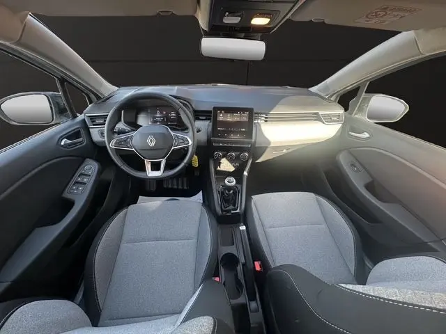 Vue intérieure avant de la Renault Clio V blanche, volant textile, tableau de bord numérique et écran tactile central.