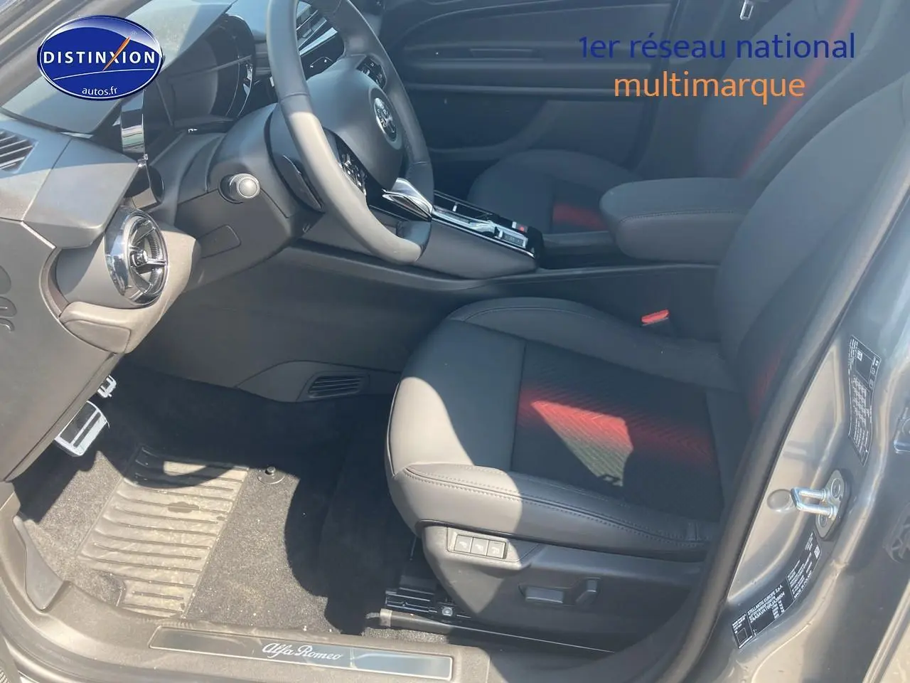 Vue intérieure côté conducteur de l'Alfa Romeo Junior 1.2 hybride 2026 gris t/noir, avec sièges cuir et commandes électriques.