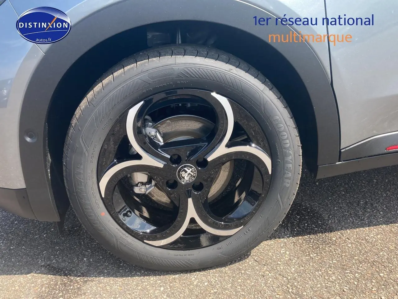 Gros plan sur la roue avant gauche de l'Alfa Romeo Junior 1.2 hybride gris t/noir avec jante alliage noire et argent.