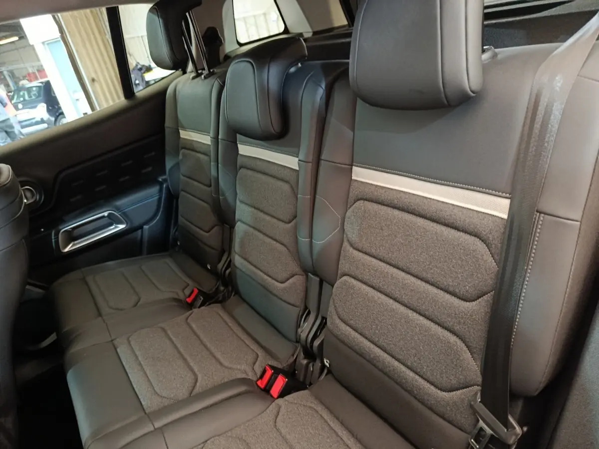 Vue intérieure des sièges arrière en tissu et cuir noir du Citroën C5 Aircross 2024, avec ceintures et appuie-têtes visibles.