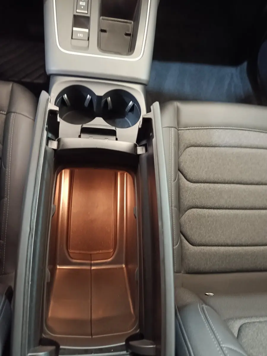 Vue plongeante sur la console centrale ouverte du Citroën C5 Aircross 2024, intérieur gris avec porte-gobelets visibles.