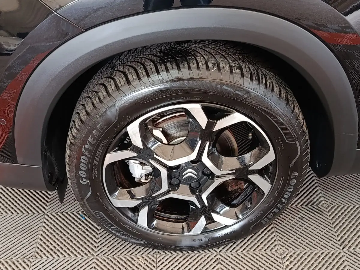 Gros plan sur la roue avant gauche noire du Citroën C5 Aircross 2024 avec jante alliage bicolore et pneu Goodyear.