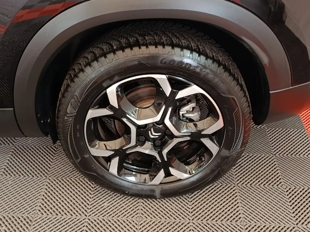 Gros plan sur la roue avant droite noire du Citroën C5 Aircross 2024 avec jante alliage bicolore et pneu Goodyear.