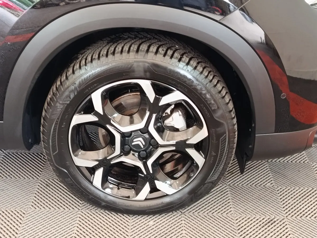 Gros plan sur la roue avant droite noire d'un Citroën C5 Aircross 2024 avec jante alliage bicolore distinctive.