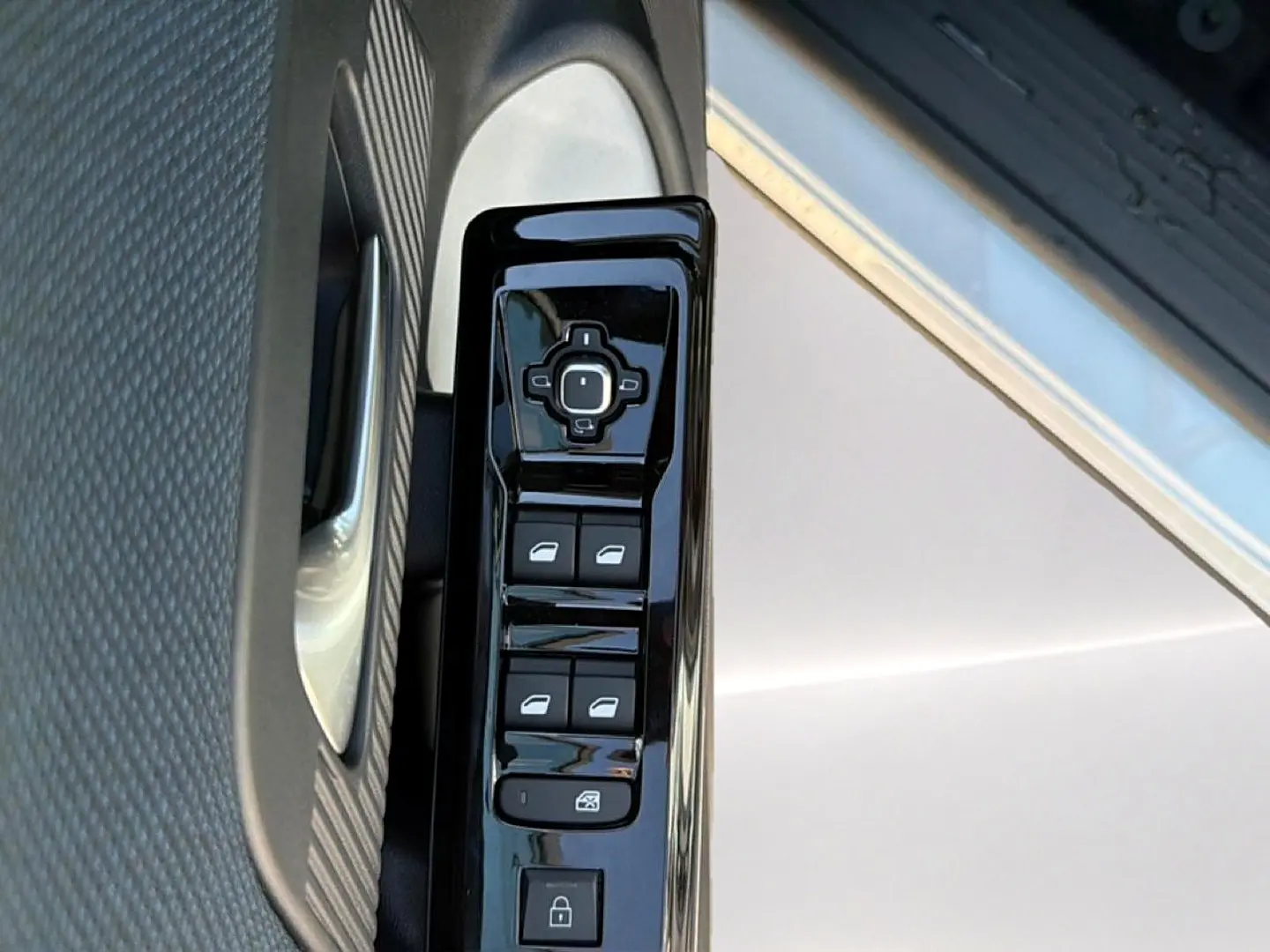 Gros plan sur les commandes de lève-vitres et rétroviseurs côté conducteur d'une Citroën C5 Aircross blanc et noir.