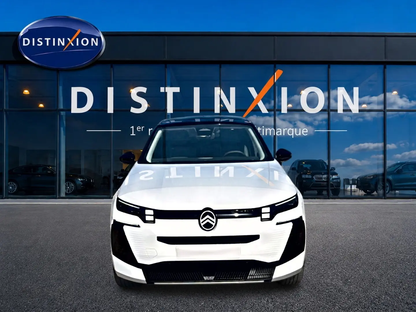 Vue frontale d'un Citroën C5 Aircross 2026 blanc avec toit noir, devant une vitrine au logo Distinxion.