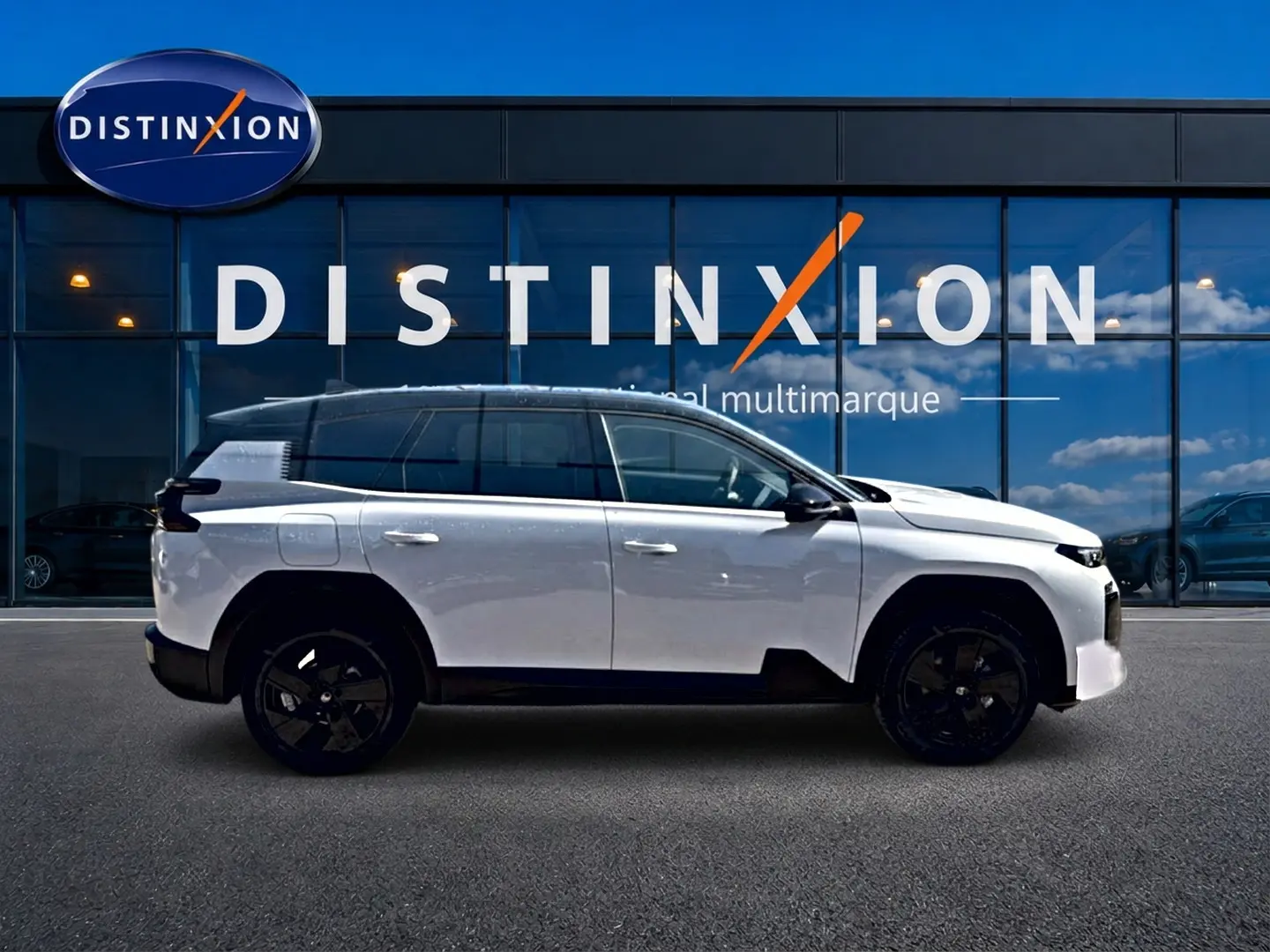 Profil droit du Citroën C5 Aircross hybride blanc avec toit noir et jantes alliage noires devant une vitrine Distinxion.
