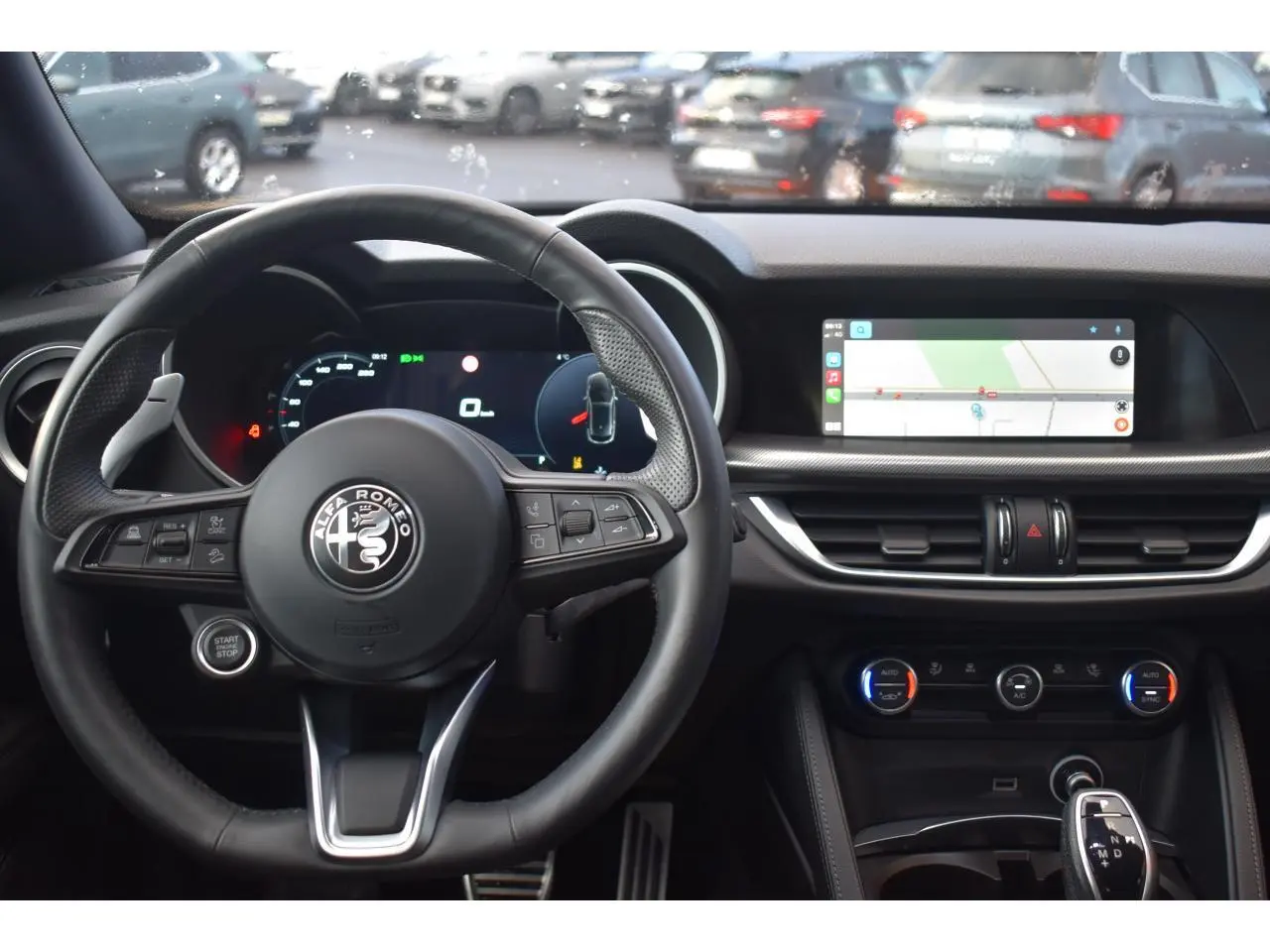 Vue intérieure centrée sur le volant Alfa Romeo Stelvio 2024 avec tableau de bord numérique et écran tactile navigation.