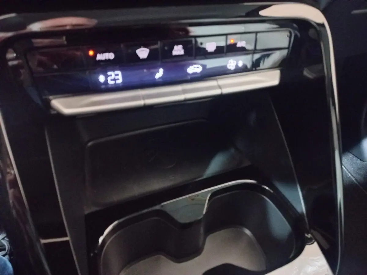 Gros plan sur la console centrale de la Citroën C3 hybride 2025 gris foncé, avec zone de recharge par induction et commandes tactiles.