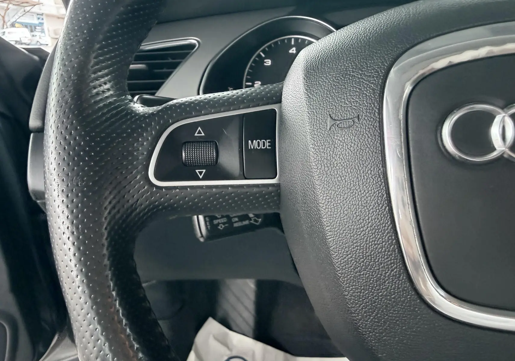 Gros plan sur le volant en cuir noir perforé de l'Audi A5 Sportback avec commandes intégrées côté gauche.