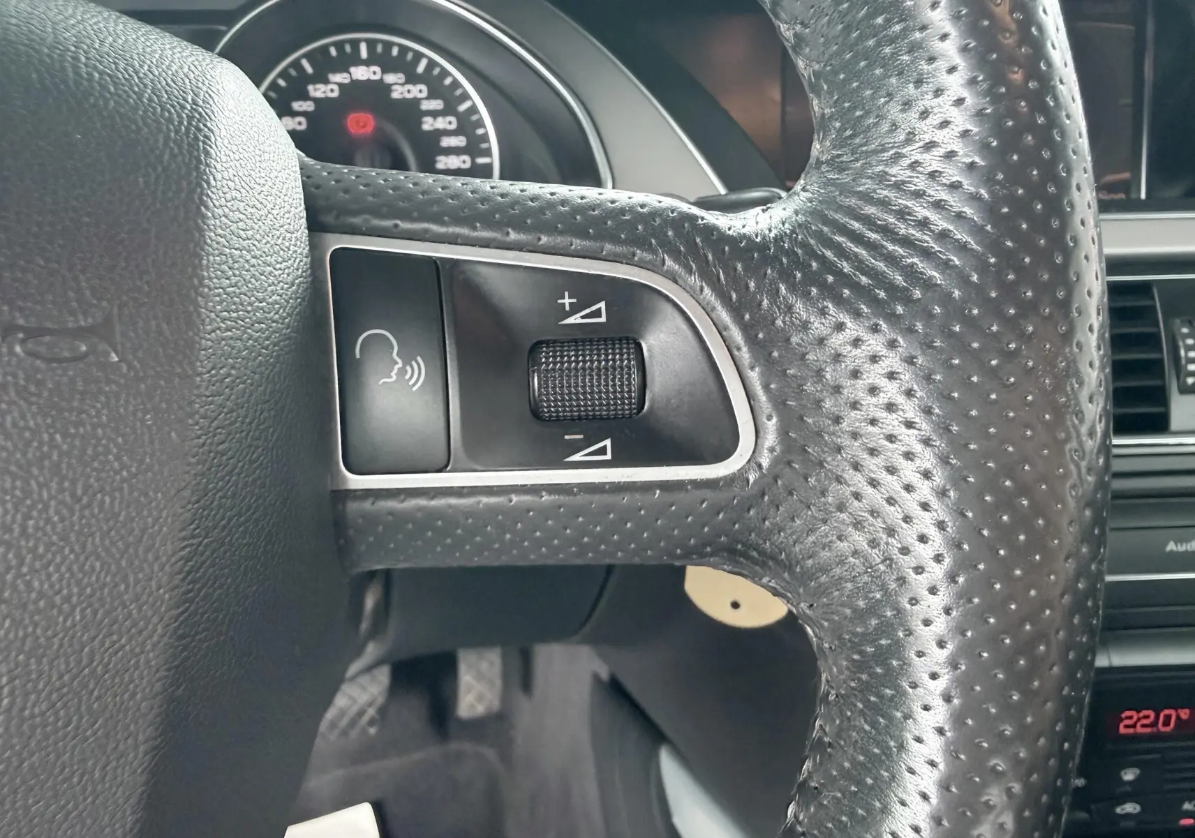 Gros plan sur le volant en cuir perforé côté gauche de l'Audi A5 Sportback avec commandes audio intégrées.