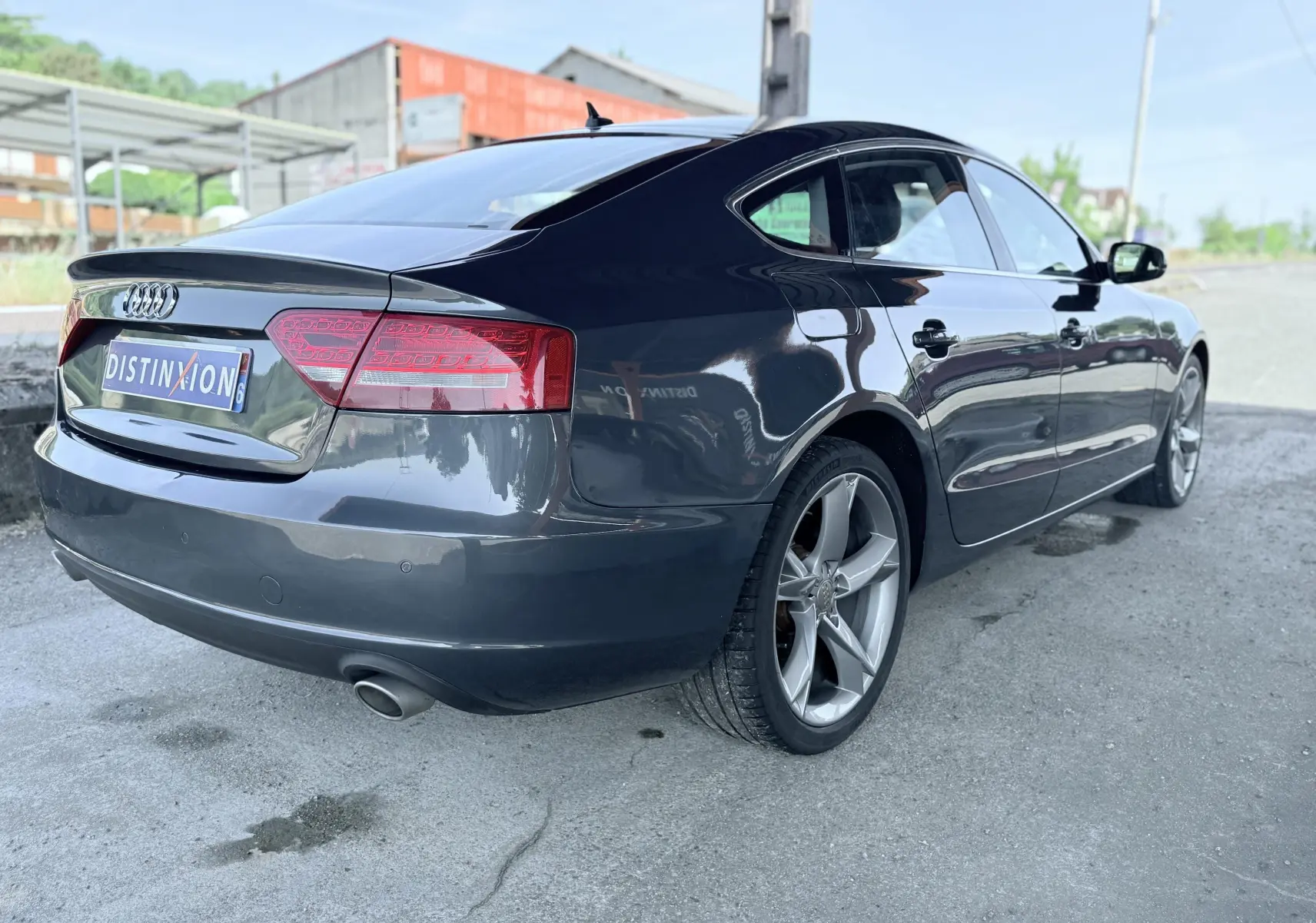 Audi A5 Sportback gris dauphin vue 3/4 arrière droit, avec jantes alliage et feux arrière LED distinctifs.