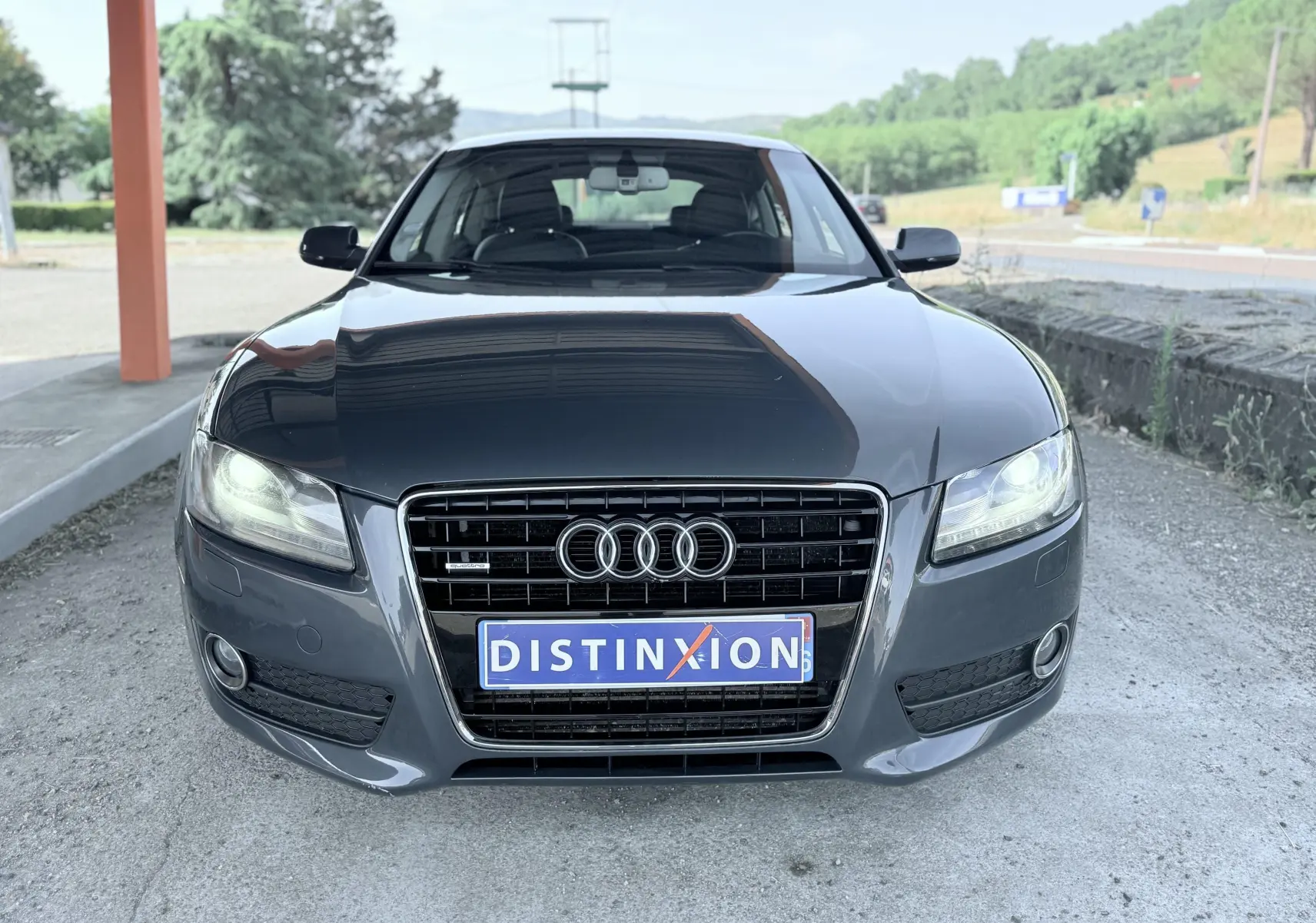 Vue avant d'une Audi A5 Sportback gris dauphin de 2009 avec calandre distinctive et phares allumés.
