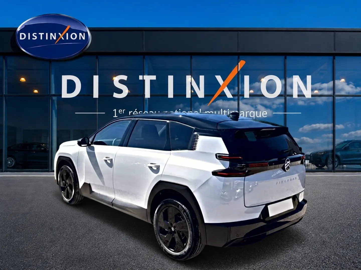 Vue 3/4 arrière droite du Citroën C5 Aircross 2026 blanc avec toit noir et jantes alliage noires devant un showroom Distinxion.