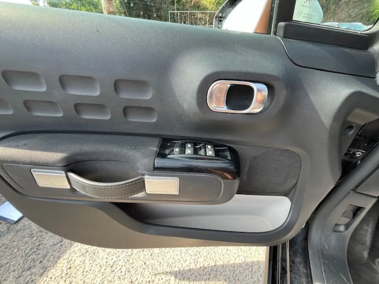 Intérieur côté gauche de la porte avant d'une Citroën C3 noire 2023, avec commandes de vitres et poignée design.