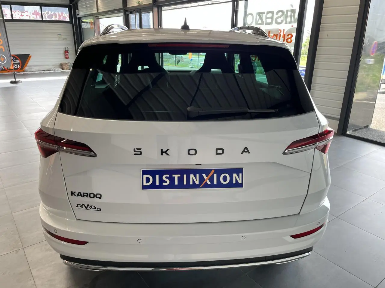 Vue arrière d'un SUV SKODA KAROQ blanc avec logo SKODA en lettres espacées et feux arrière LED fins.