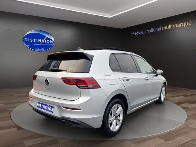 Vue 3/4 arrière droite d'une Volkswagen Golf VIII gris argent avec vitres surteintées et toit panoramique ouvrant.