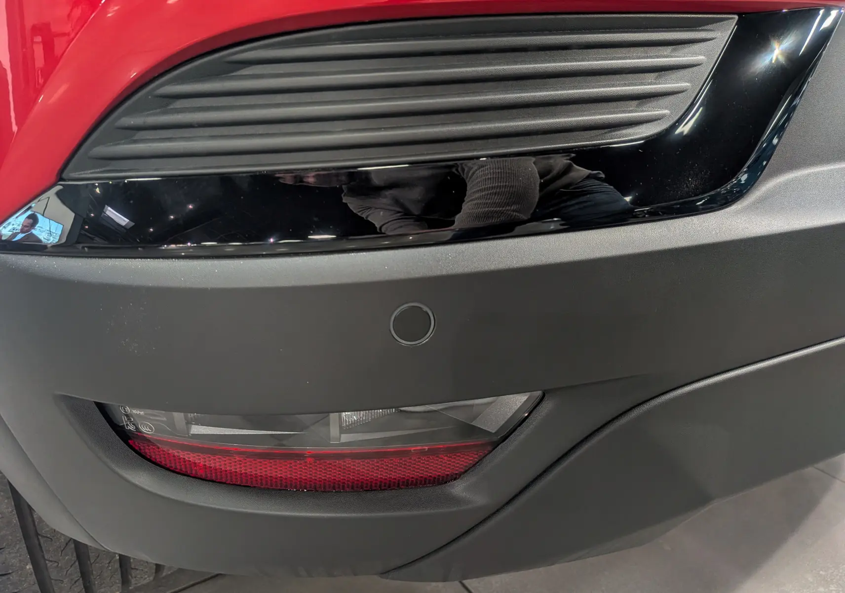 Gros plan sur le feu arrière et le pare-chocs noir du Renault Captur E-TECH rouge Flamme, détail du capteur de stationnement.