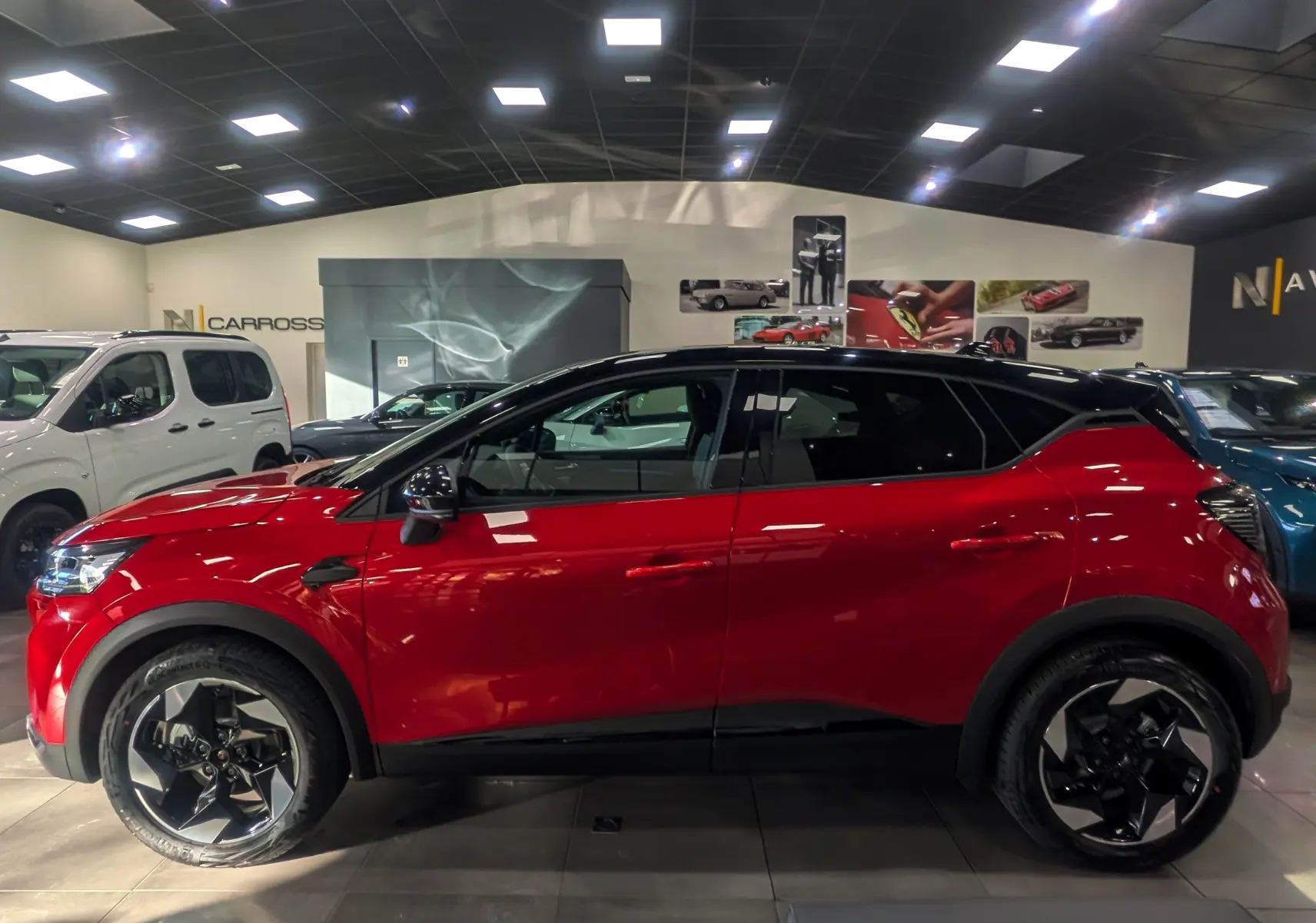 Renault Captur E-TECH hybride rouge flamme avec toit noir, vue profil côté gauche en intérieur showroom.