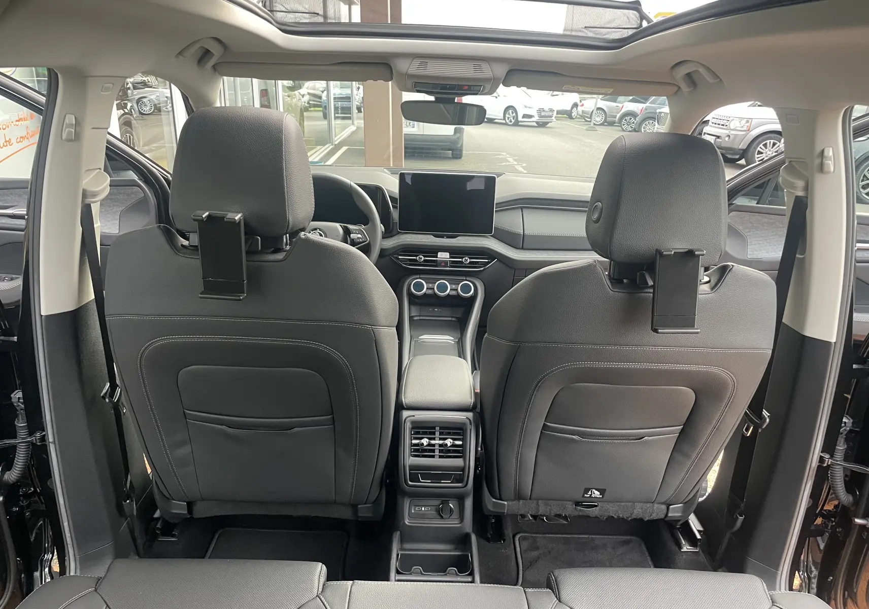 Vue intérieure arrière du Skoda Kodiaq noir métal 2024 montrant les sièges avant en cuir noir et la console centrale avec écran tactile.