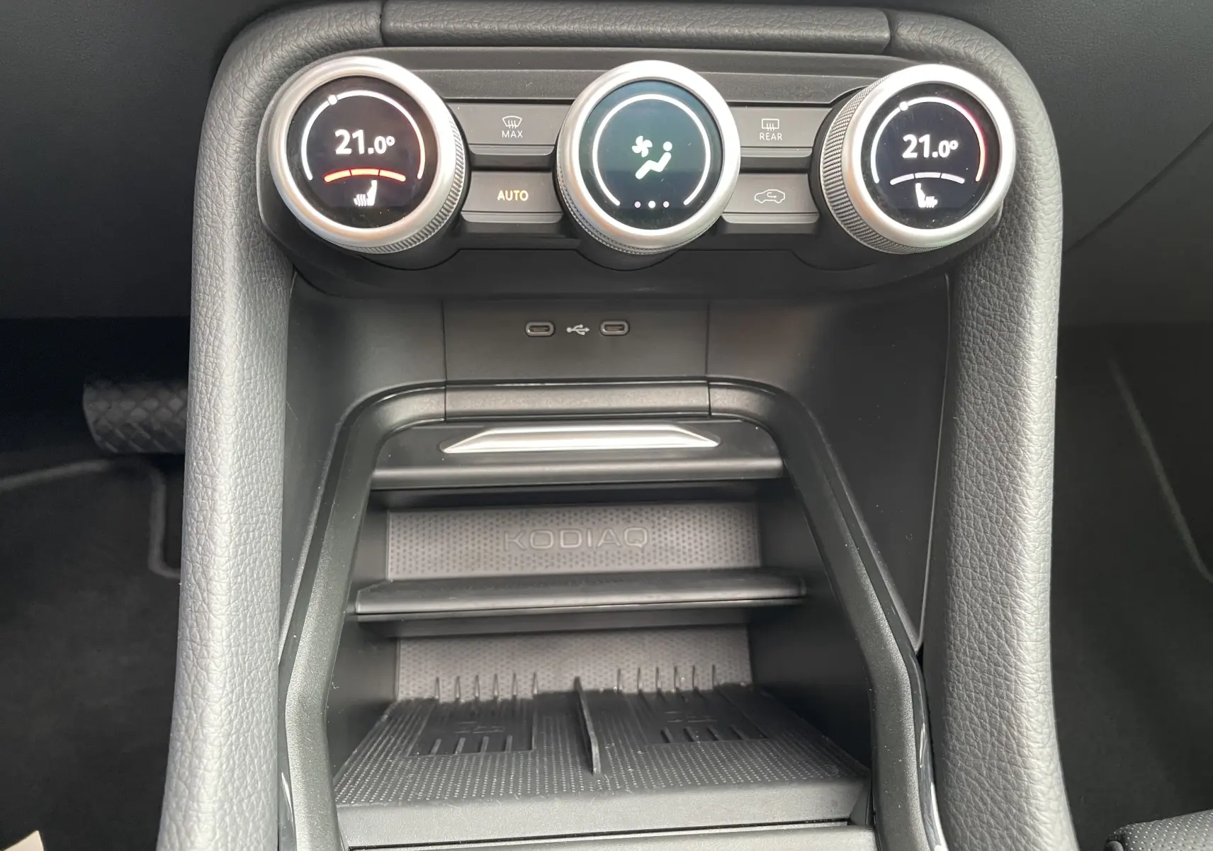 Vue rapprochée de la console centrale du Skoda Kodiaq 2024, avec commandes climatisation et zone de rangement marquée KODIAQ.