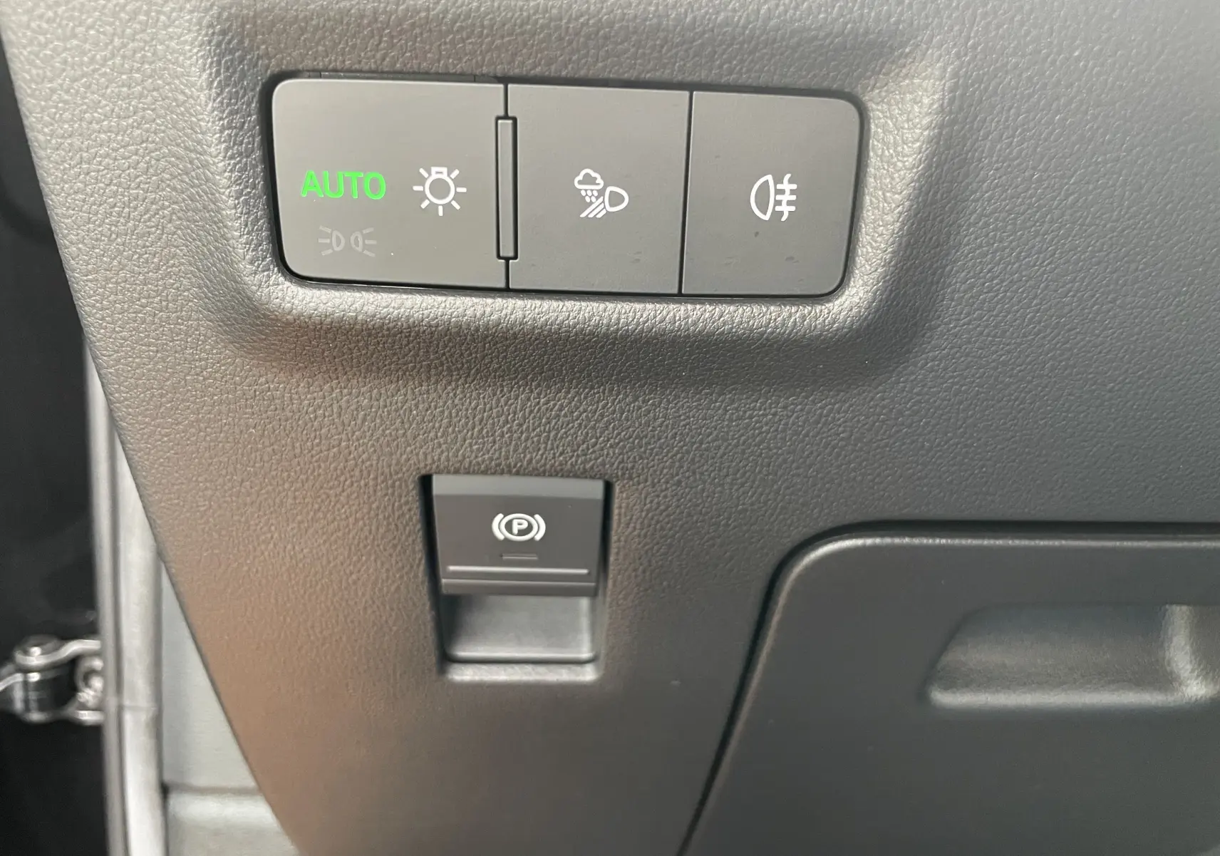 Gros plan sur les commandes d’éclairage automatiques et frein de parking électrique du Skoda Kodiaq noir métal 2024.