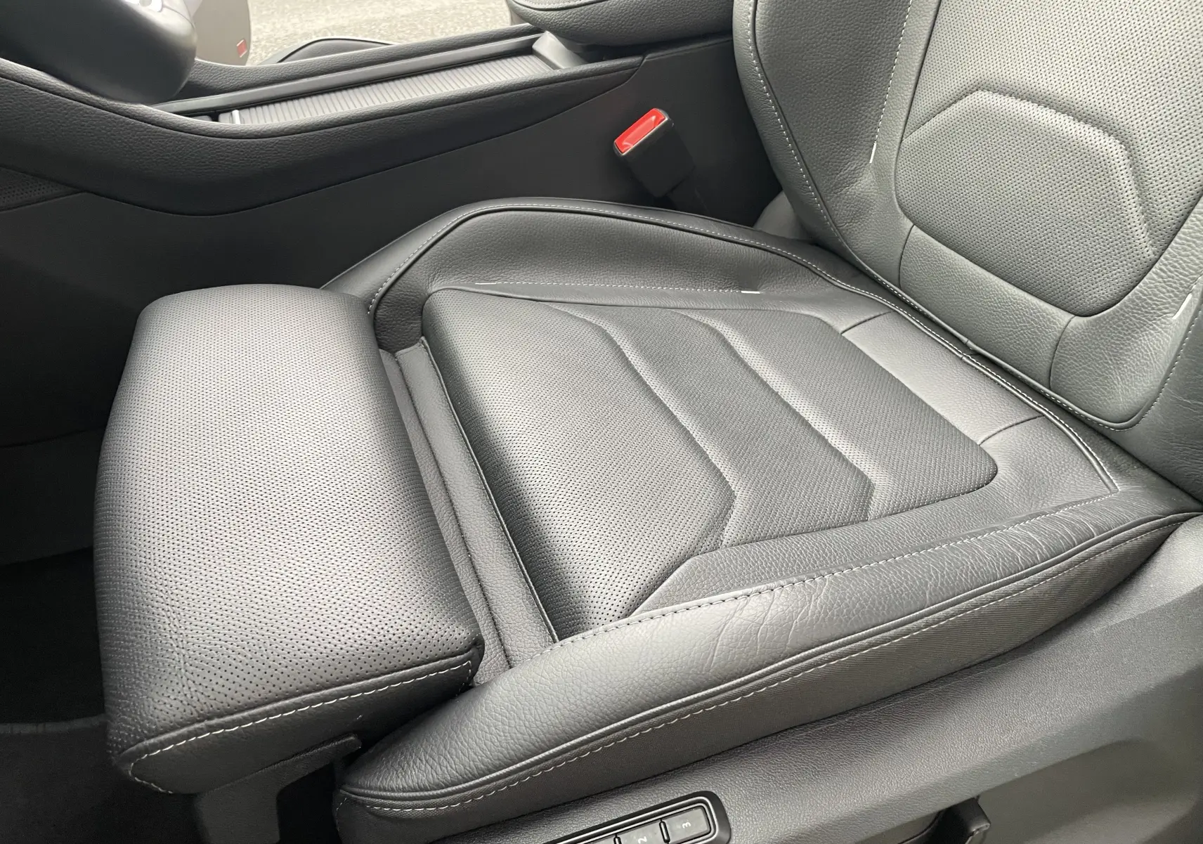 Gros plan sur le siège conducteur en cuir noir perforé du Skoda Kodiaq 2024, mettant en valeur les réglages électriques et la finition soignée.