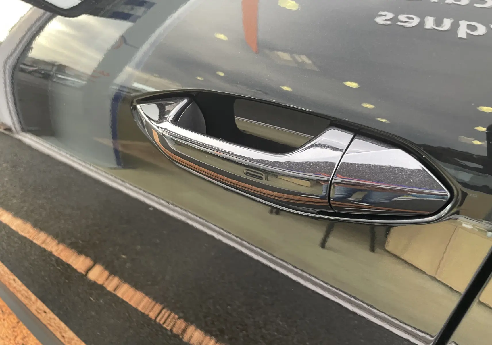 Poignée de porte chromée sur la portière noire métal d'un Skoda Kodiaq 2024, vue rapprochée côté gauche.