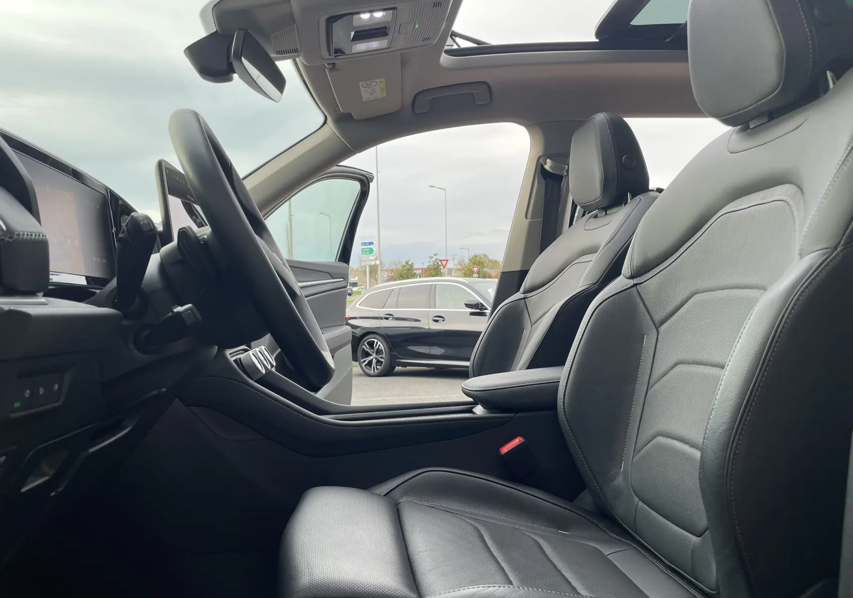 Vue intérieure côté conducteur du Skoda Kodiaq noir métal 2024, avec sièges cuir noir et toit ouvrant panoramique visible.