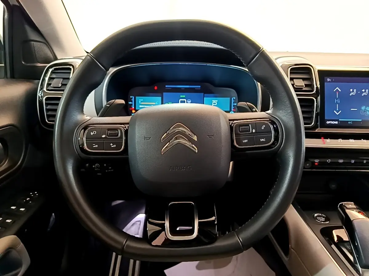 Vue intérieure centrée sur le volant cuir noir du Citroën C5 Aircross Hybrid 225 ë-EAT8 avec tableau de bord digital.