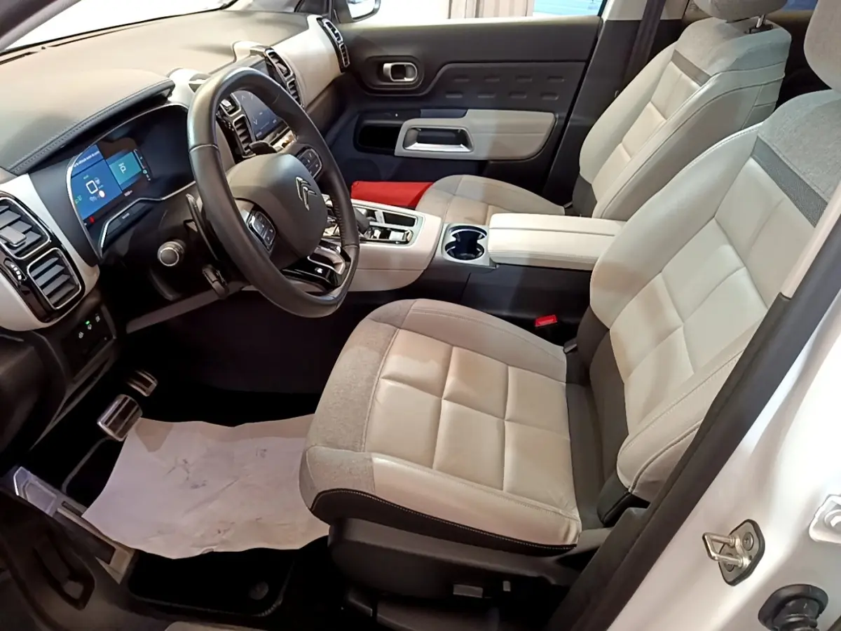 Vue intérieure côté conducteur du Citroën C5 Aircross Hybrid blanc, sièges bicolores et tableau de bord avec écran tactile.
