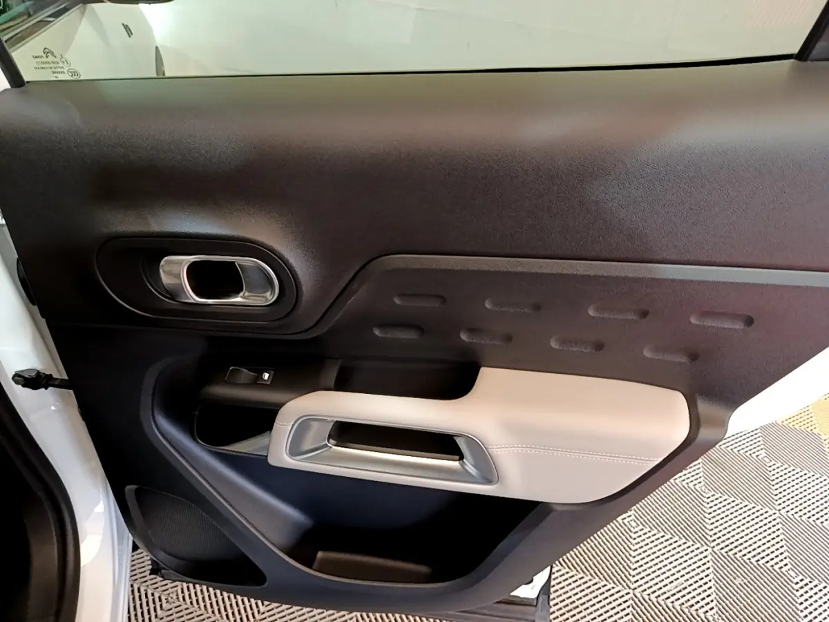 Gros plan sur la porte intérieure côté gauche du Citroën C5 Aircross Hybrid blanc, avec accoudoir beige et poignée argentée.