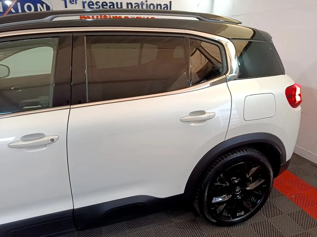 Vue côté droit arrière du Citroën C5 Aircross Hybrid blanc avec toit noir et jantes noires brillantes.