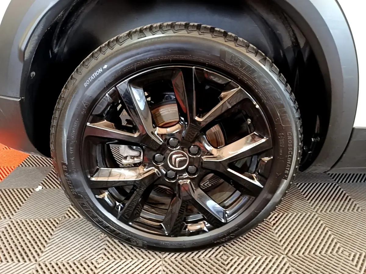 Gros plan sur la roue avant droite noire brillante du Citroën C5 Aircross blanc hybride rechargeable.