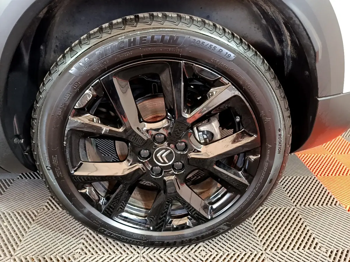 Gros plan sur la roue avant droite noire brillante du Citroën C5 Aircross Hybrid 225 ë-EAT8 Shine Pack blanc.