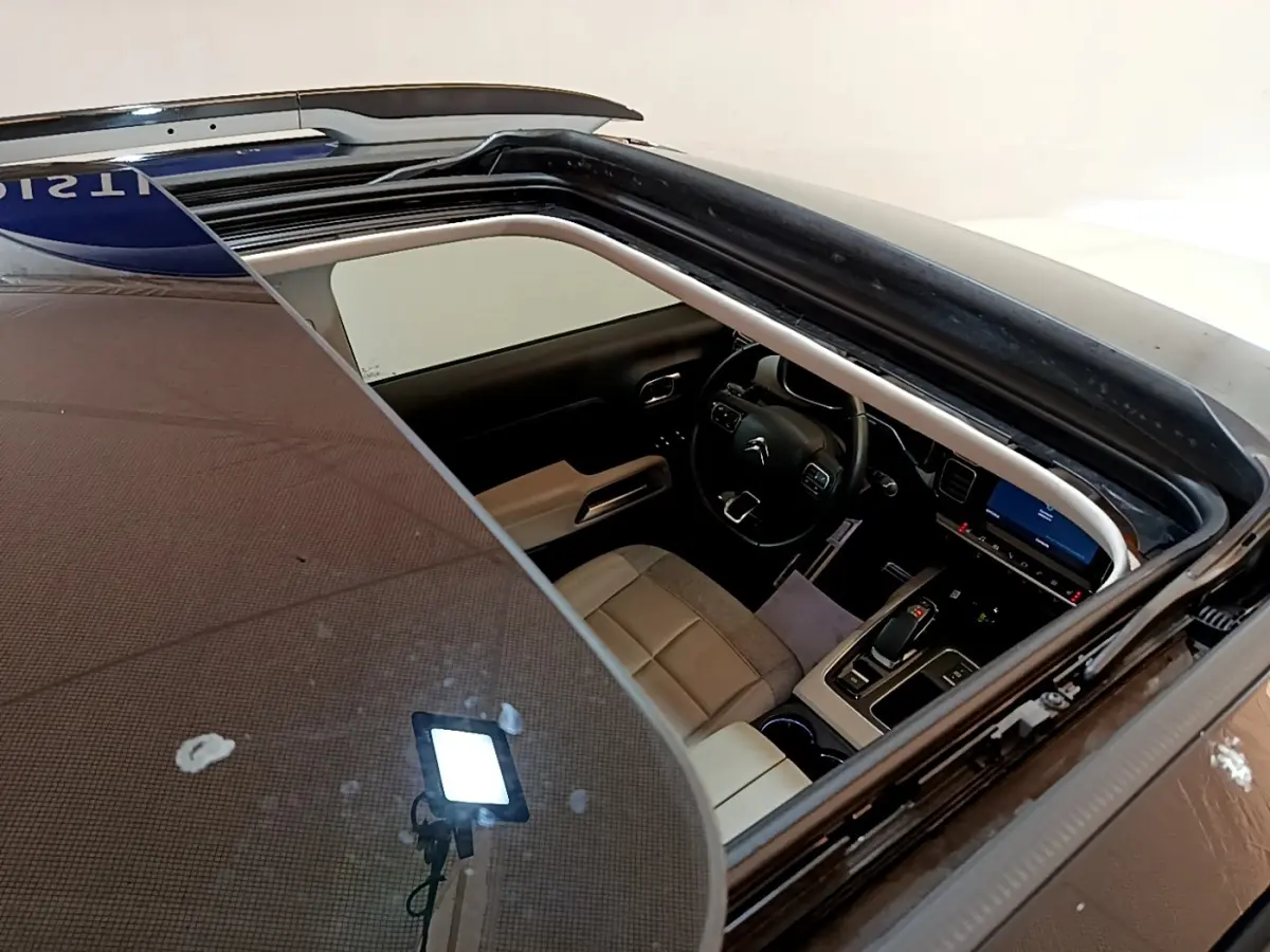 Vue plongeante sur l'intérieur beige et noir du Citroën C5 Aircross blanc via son toit ouvrant panoramique.