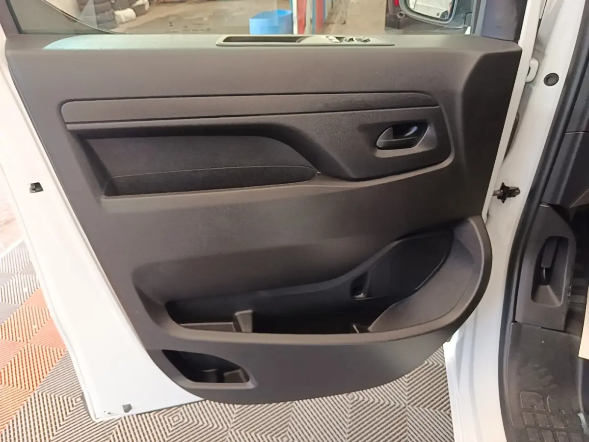 Vue intérieure côté gauche de la porte avant blanche du Peugeot Expert Fourgon avec panneau noir et rangements intégrés.