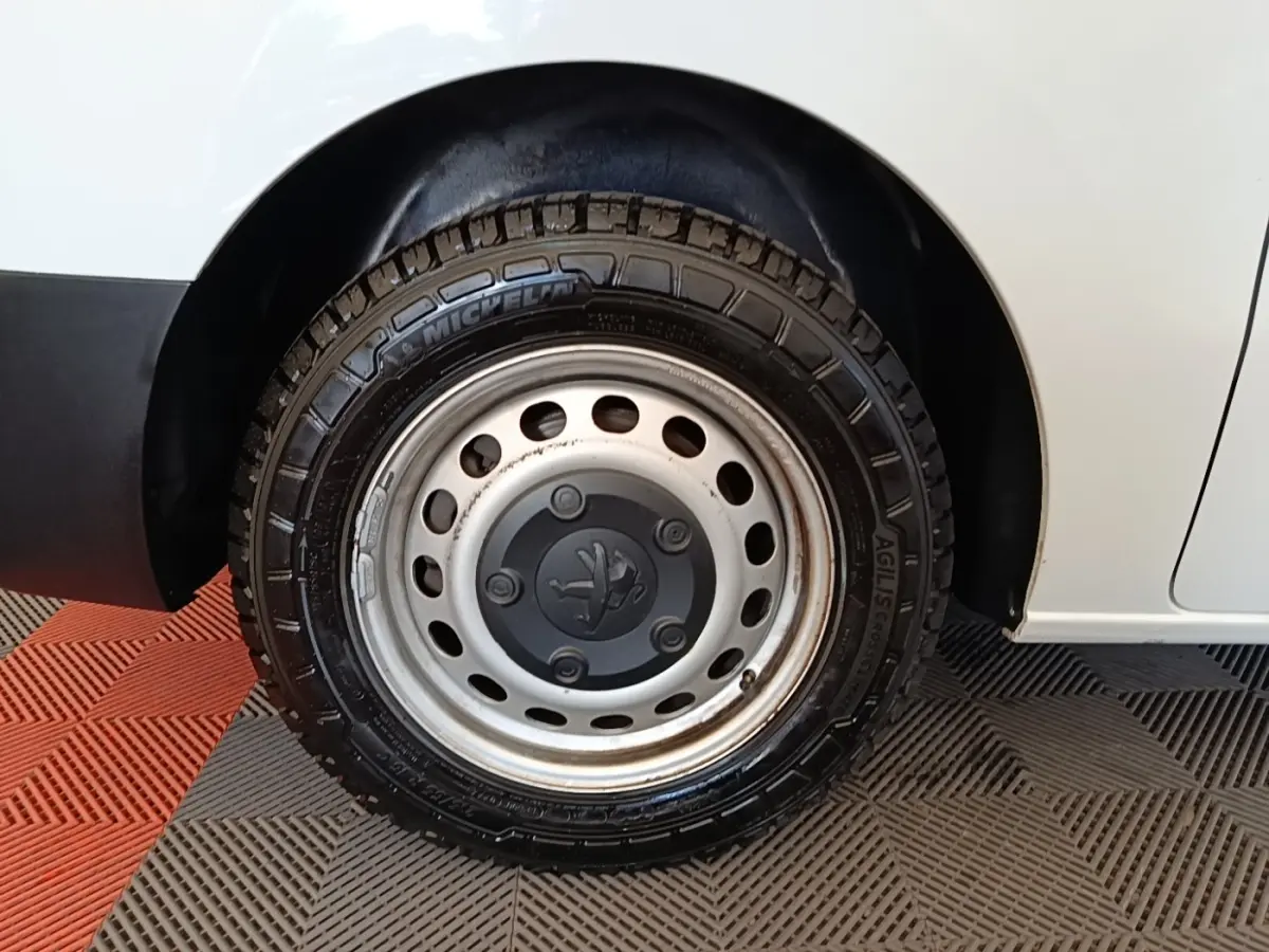 Gros plan sur la roue arrière droite d’un Peugeot Expert Fourgon blanc, jante acier avec logo Peugeot central.