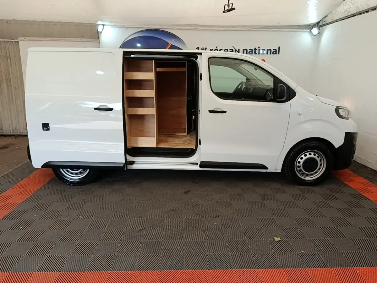 Vue latérale droite d’un Peugeot Expert Fourgon blanc 2023 avec porte coulissante ouverte révélant un aménagement bois intérieur.