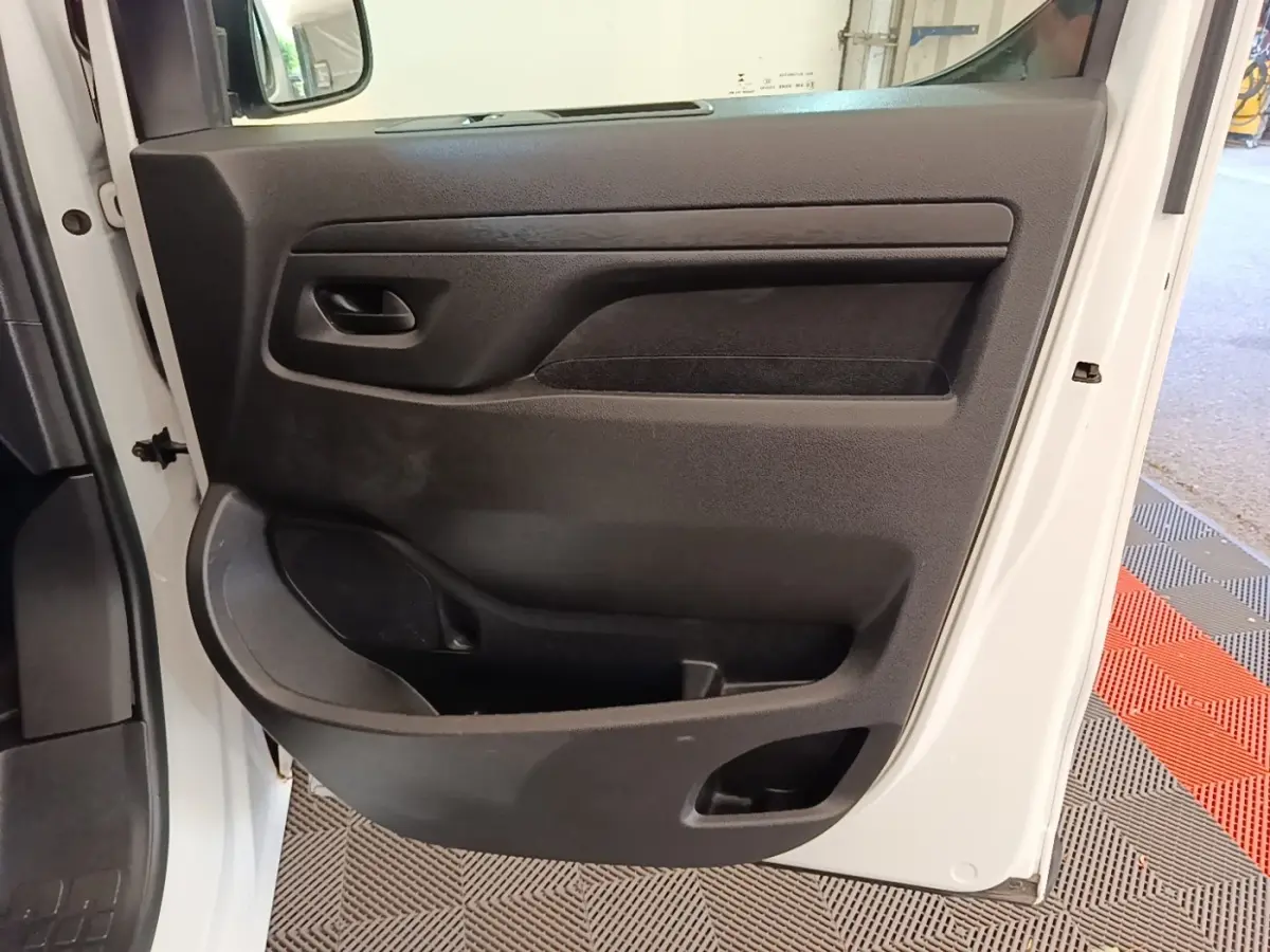 Vue rapprochée de la porte avant gauche ouverte du Peugeot Expert Fourgon blanc, montrant la garniture intérieure noire.