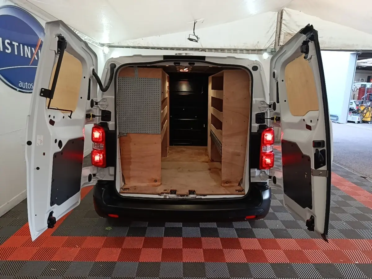 Vue arrière du Peugeot Expert Fourgon blanc 2023 avec portes ouvertes et aménagements bois dans l’espace de chargement.