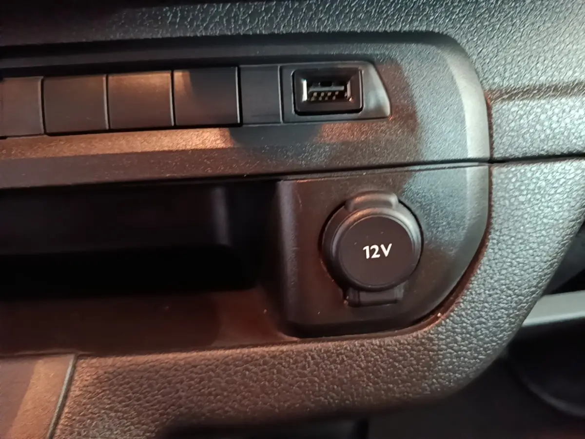 Gros plan sur la prise 12V et port USB du tableau de bord noir du Peugeot Expert Fourgon blanc 2023.