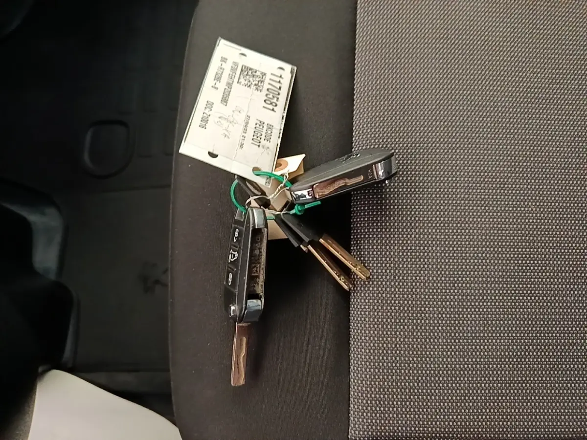 Clés de véhicule Peugeot Expert Fourgon posées sur un siège intérieur en tissu gris foncé.