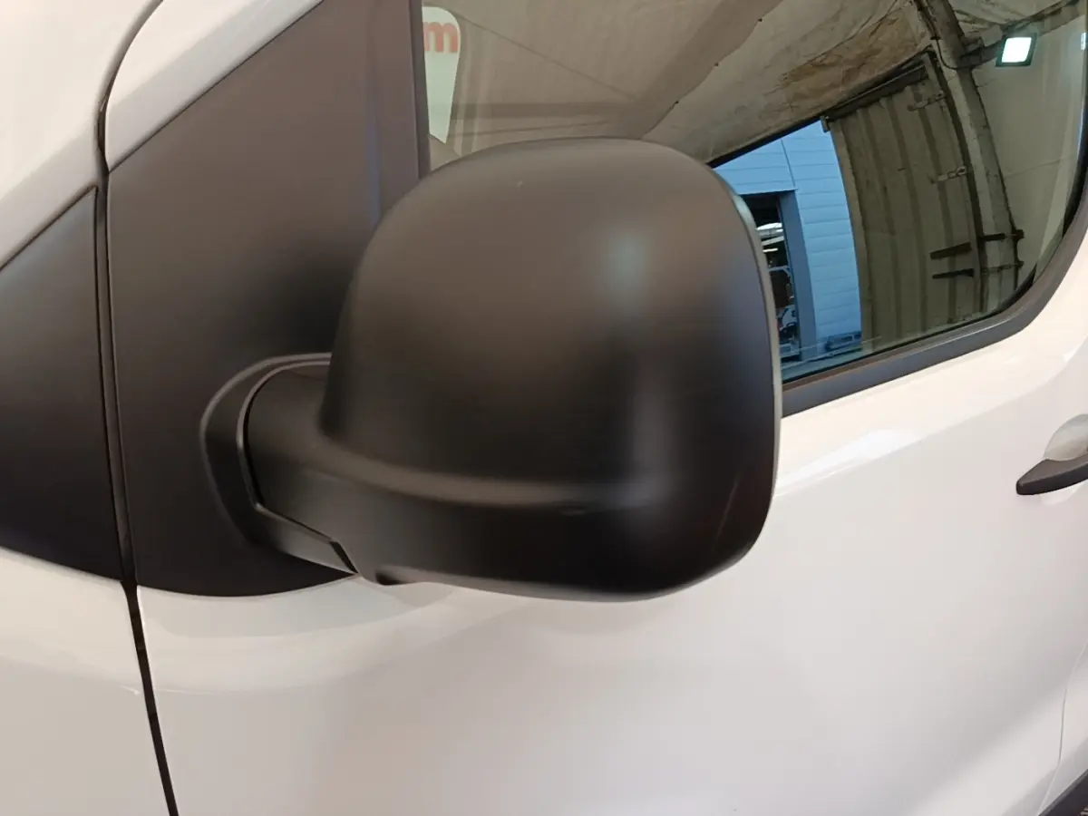 Gros plan sur le rétroviseur noir côté droit du Peugeot Expert Fourgon blanc, avec vitre et porte avant visibles.