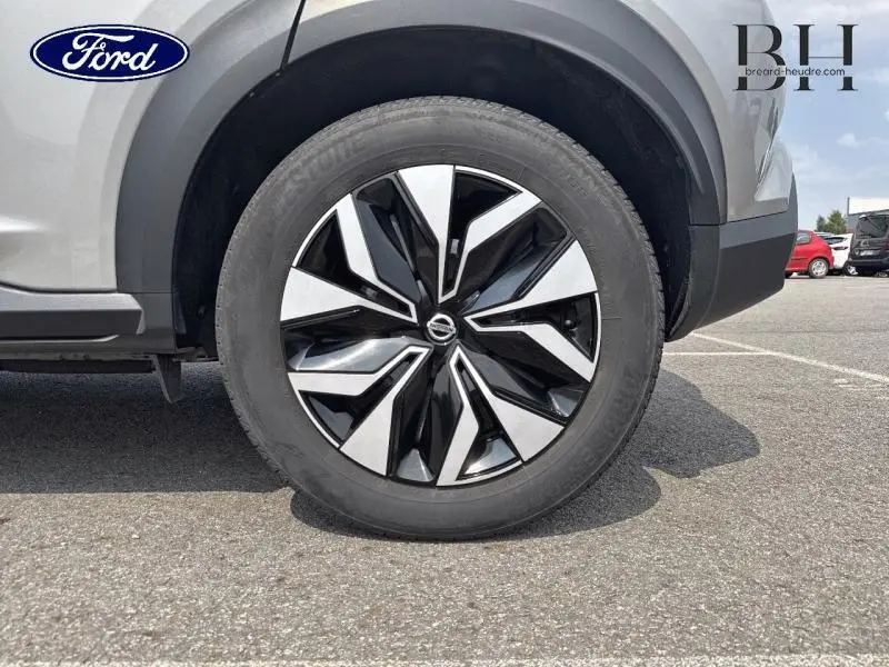 Gros plan sur la roue avant droite du Nissan Juke gris perle métallisé avec jante noire et argentée au design moderne.