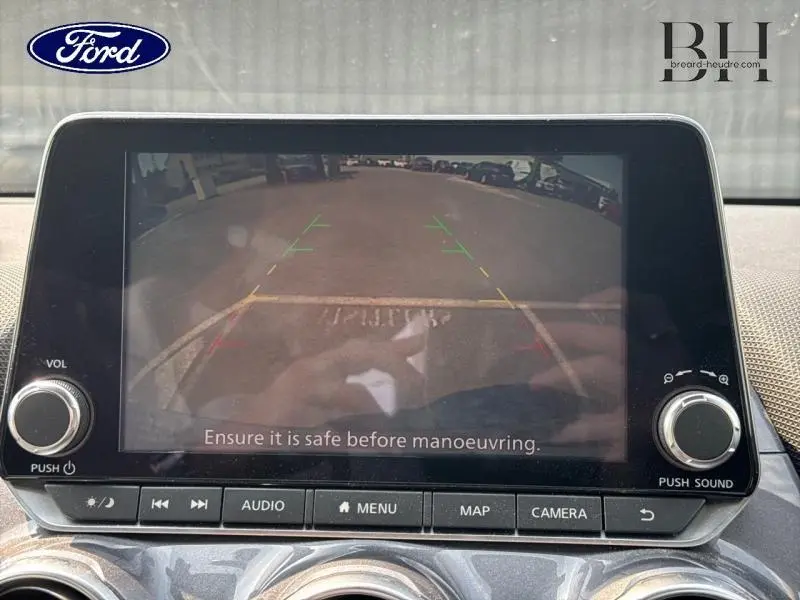 Écran tactile de caméra de recul d'une Nissan Juke gris perle, affichant la vue arrière avec lignes de guidage colorées.