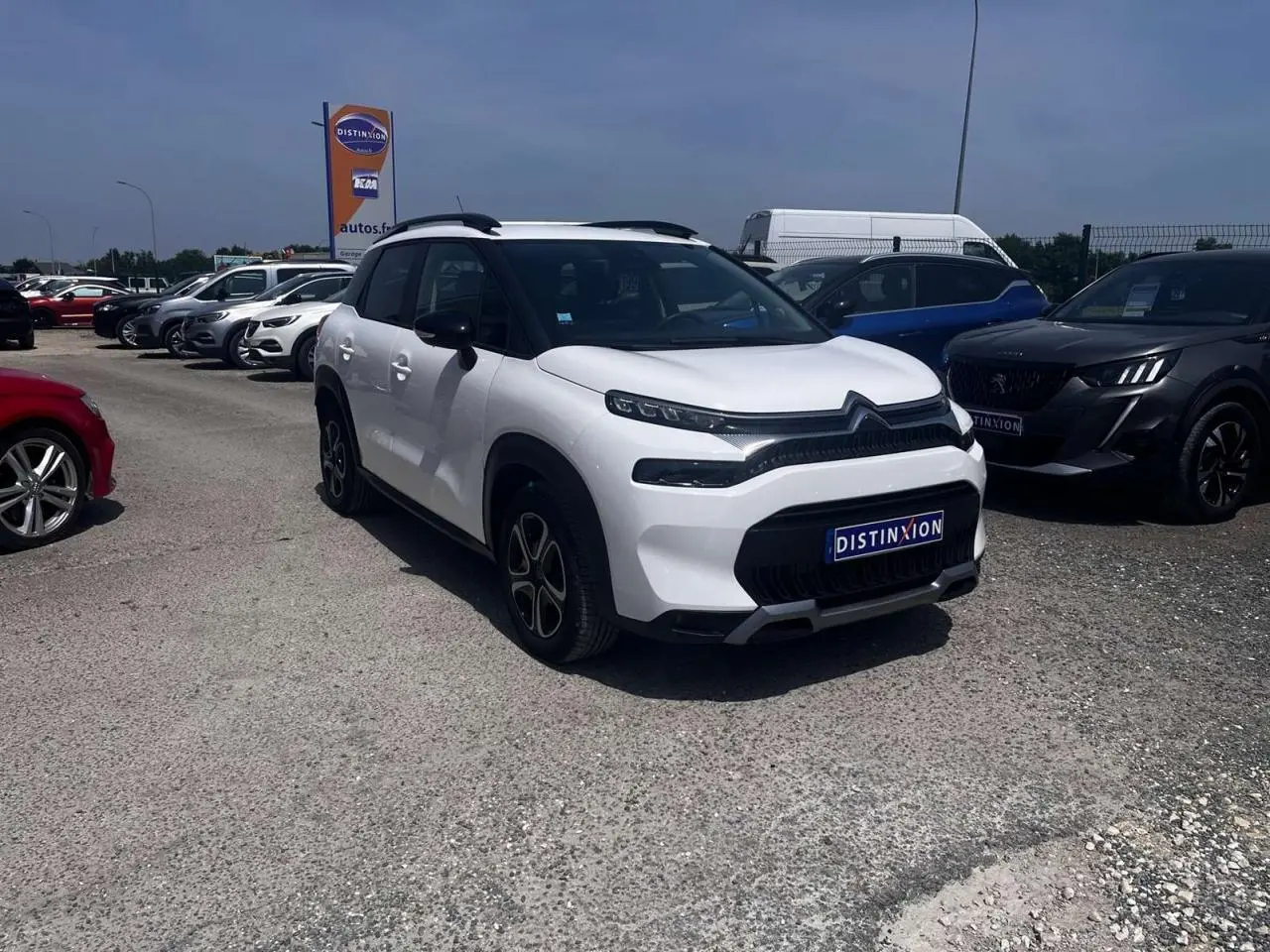 Citroën C3 Aircross blanc banquise en 3/4 avant droit avec barres de toit noir brillant sur parking.